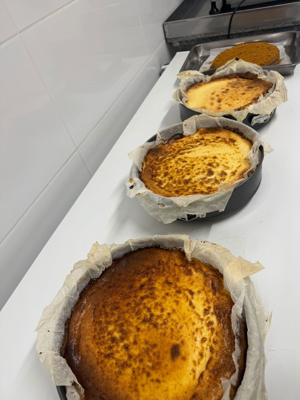 Tartas de queso recién horneadas en sus moldes, con la superficie tostada